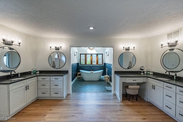 bathroom featuring two vanities, a sink, and wood finished floors