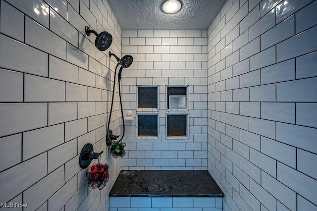 bathroom with a textured ceiling and a tile shower