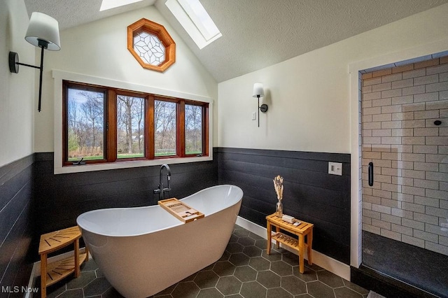 full bathroom with a stall shower, a textured ceiling, wainscoting, lofted ceiling with skylight, and a freestanding bath