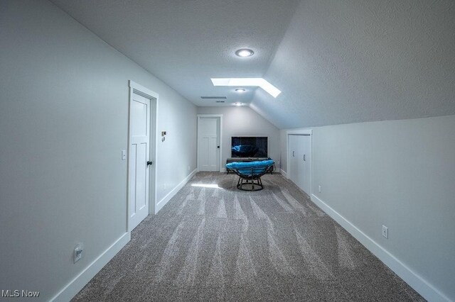 bonus room with a textured ceiling, carpet flooring, baseboards, and lofted ceiling with skylight