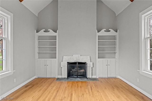 2484 Eaton Rd, University Heights, OH 44118 - unfurnished living room with vaulted ceiling, built in shelves, wood finished floors, a fireplace with flush hearth, and baseboards