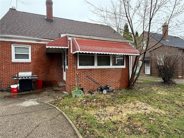 20614 Kings Hwy, Warrensville Heights, OH 44122 - view of front of house featuring brick siding, a front lawn, a chimney, and a shingled roof
