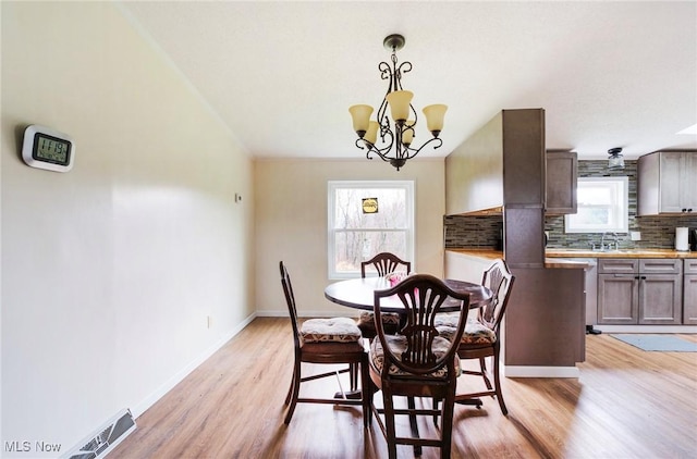 dining area featuring a wealth of natural light, light wood-style floors, baseboards, and an inviting chandelier