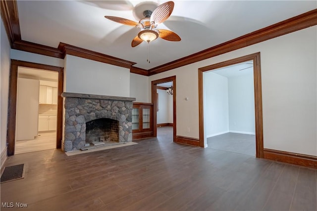 unfurnished living room featuring a stone fireplace, ornamental molding, a ceiling fan, visible vents, and wood finished floors
