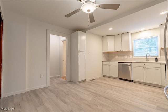 kitchen with stainless steel dishwasher, light wood-type flooring, light countertops, a sink, and backsplash