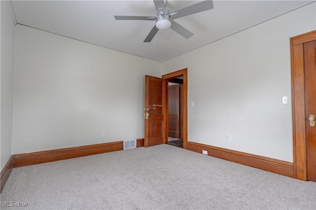 unfurnished room with carpet, visible vents, baseboards, and a ceiling fan