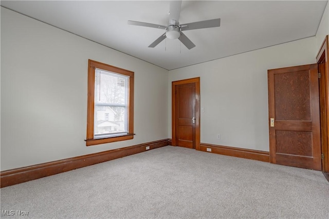 carpeted empty room with baseboards and a ceiling fan