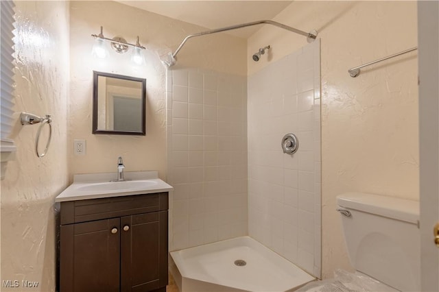 full bath featuring vanity, a tile shower, and toilet