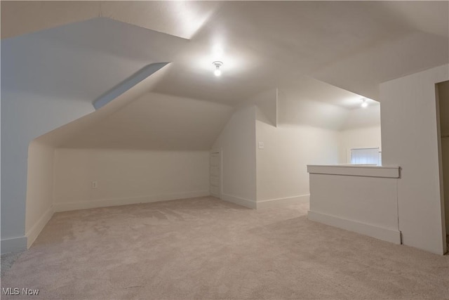 additional living space featuring carpet flooring, baseboards, and vaulted ceiling