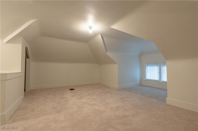 additional living space with baseboards, lofted ceiling, and carpet floors
