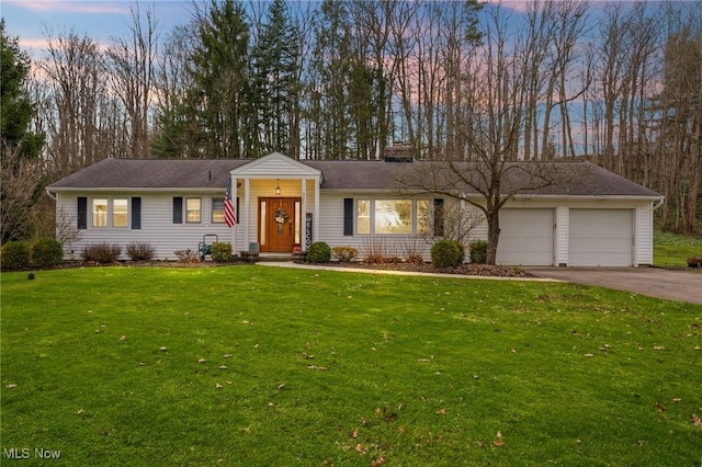 ranch-style home featuring a chimney, a garage, concrete driveway, and a front lawn