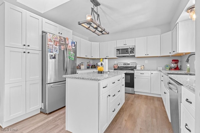 7319 Guilford Rd, Seville, OH 44273 - kitchen with a center island, white cabinets, a sink, light wood-type flooring, and appliances with stainless steel finishes