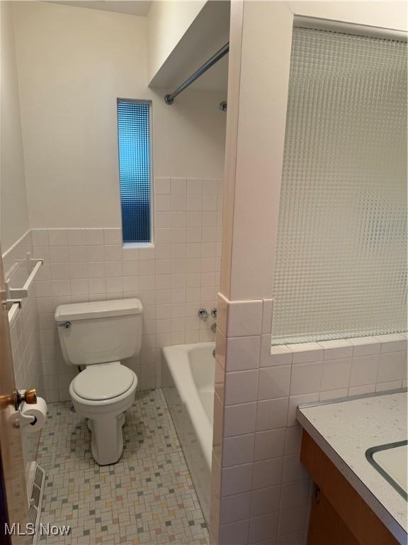 4830 Autumn Ln, Brooklyn, OH 44144 - bathroom featuring vanity, a wainscoted wall, toilet, tile walls, and a bathtub
