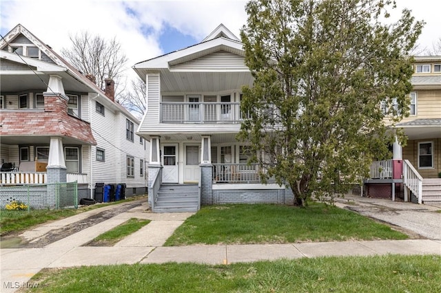view of front of home with a balcony, a front lawn, and covered porch