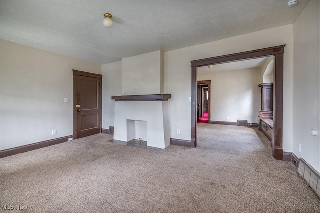 unfurnished living room featuring carpet and baseboards