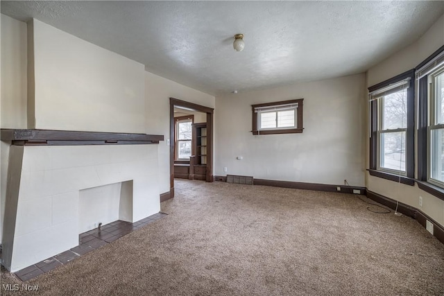 unfurnished living room featuring dark colored carpet, a textured ceiling, and baseboards