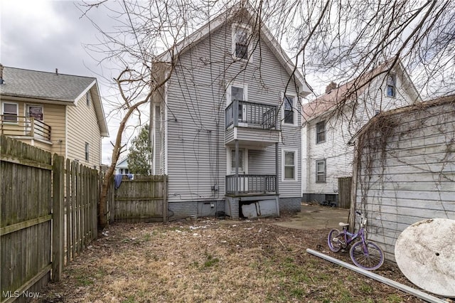 back of property featuring a fenced backyard, crawl space, and a balcony