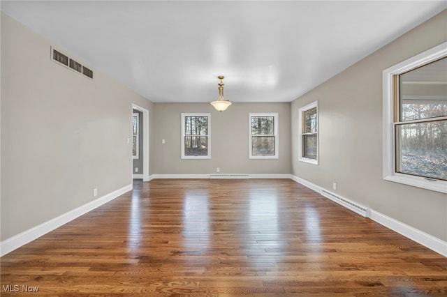 unfurnished room featuring wood finished floors, baseboards, and visible vents