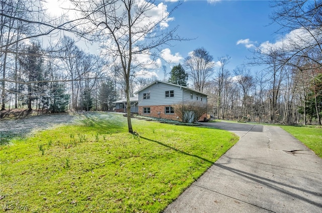 view of side of property featuring brick siding, driveway, and a lawn