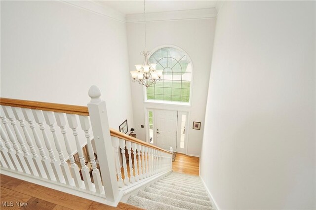 4339 Sierra Dr, Copley, OH 44321 - stairs featuring wood finished floors, a high ceiling, a notable chandelier, and crown molding