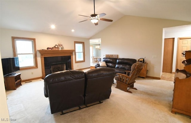 living area with light carpet, a wealth of natural light, ceiling fan with notable chandelier, and lofted ceiling