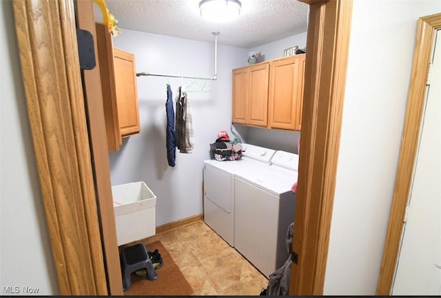 laundry room featuring a textured ceiling, washing machine and clothes dryer, a sink, baseboards, and cabinet space
