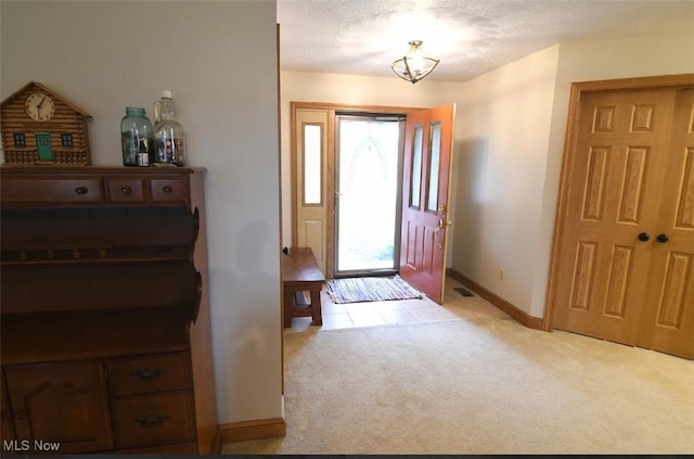 entrance foyer with a chandelier, baseboards, light colored carpet, and a textured ceiling