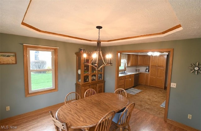 dining area with baseboards, a textured ceiling, and a raised ceiling