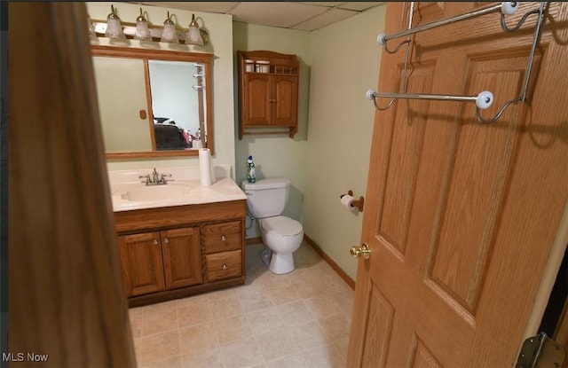 bathroom with toilet, a paneled ceiling, and vanity