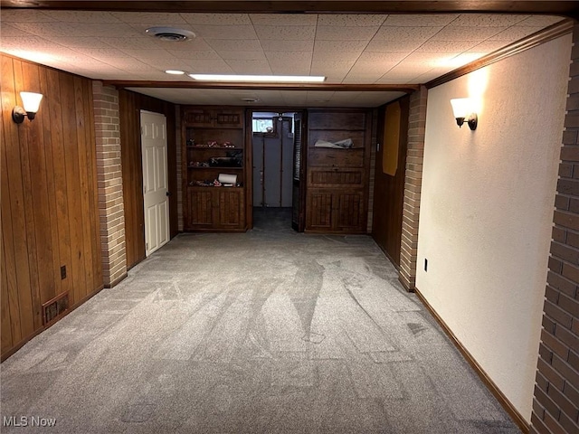 interior space featuring wood walls, light colored carpet, and visible vents