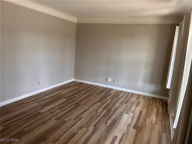 unfurnished room with dark wood-style floors, baseboards, and crown molding