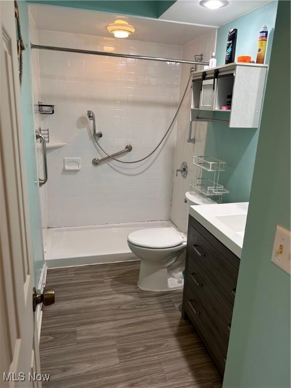 bathroom with a shower stall, vanity, toilet, and wood finished floors