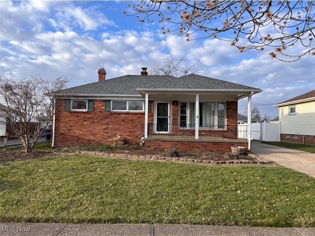 view of front of house with a chimney, a front yard, brick siding, fence, and covered porch