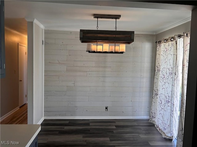 unfurnished dining area featuring wood walls, baseboards, ornamental molding, and dark wood finished floors