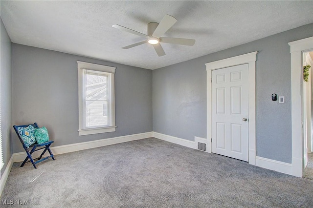 unfurnished room featuring carpet flooring, visible vents, a textured ceiling, and a ceiling fan
