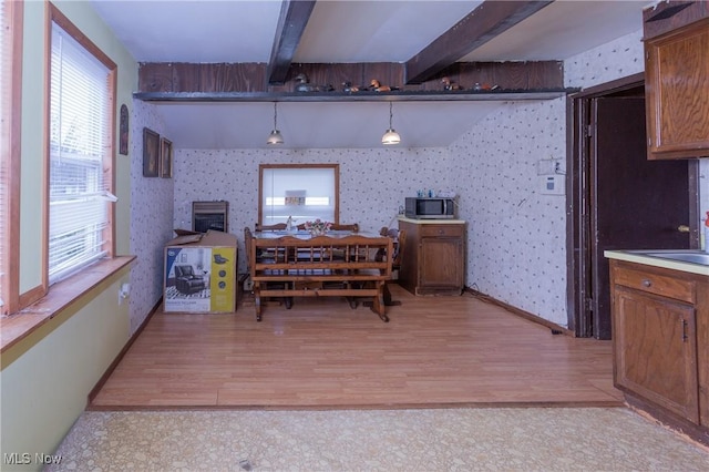 dining room with wallpapered walls, light wood finished floors, and beamed ceiling
