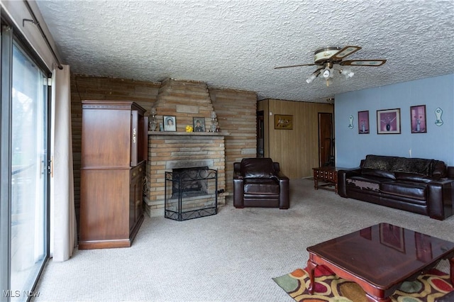 living area featuring wood walls, carpet flooring, ceiling fan, and a fireplace