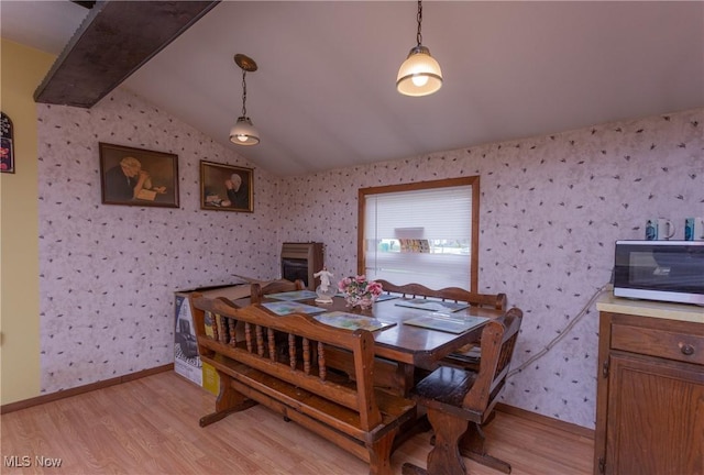 dining room featuring light wood-style flooring, baseboards, wallpapered walls, and lofted ceiling with beams