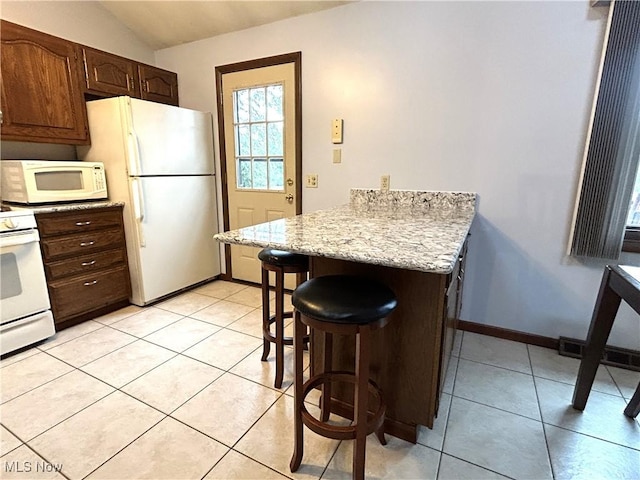 7366 Cromwell Dr, Solon, OH 44139 - kitchen with light tile patterned floors, white appliances, a peninsula, vaulted ceiling, and a breakfast bar area