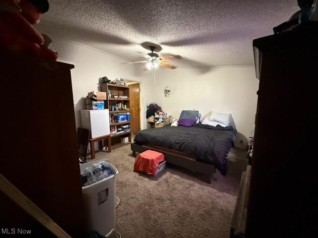 carpeted bedroom with a ceiling fan and a textured ceiling