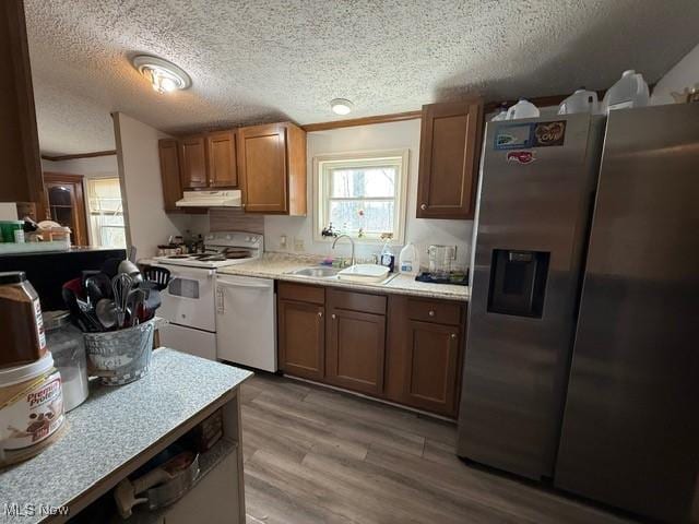 kitchen featuring stainless steel fridge, white electric stove, under cabinet range hood, dishwashing machine, and a sink