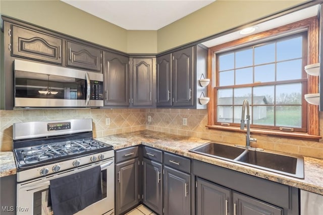 kitchen with tasteful backsplash, light countertops, a sink, and appliances with stainless steel finishes