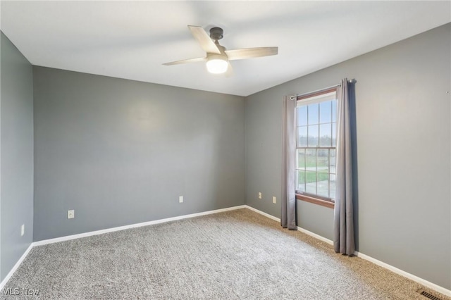 carpeted spare room featuring visible vents, ceiling fan, and baseboards