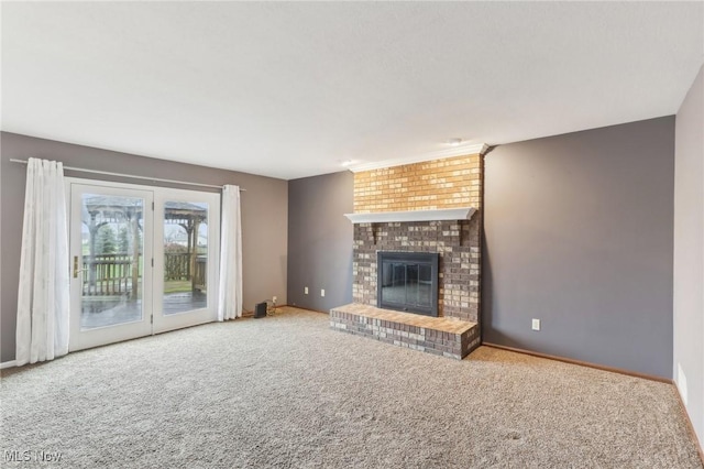 unfurnished living room featuring carpet flooring, a brick fireplace, and baseboards