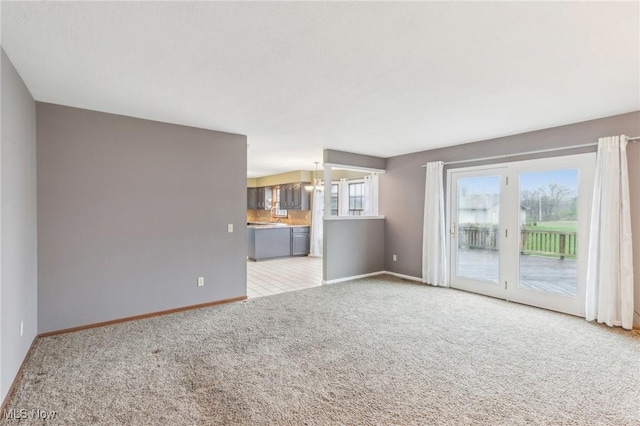 unfurnished living room featuring light colored carpet and baseboards