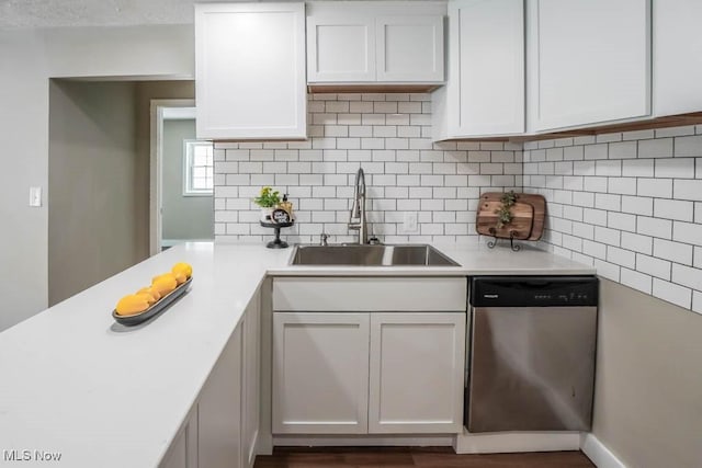 kitchen featuring stainless steel dishwasher, light countertops, a sink, and backsplash