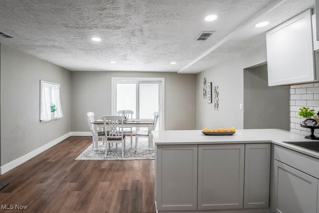 kitchen featuring dark wood-type flooring, a peninsula, visible vents, and plenty of natural light