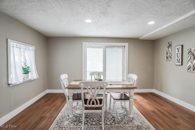 dining room featuring a wealth of natural light, a textured ceiling, baseboards, and wood finished floors