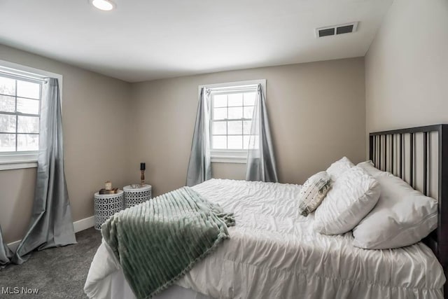 carpeted bedroom featuring baseboards, multiple windows, visible vents, and recessed lighting