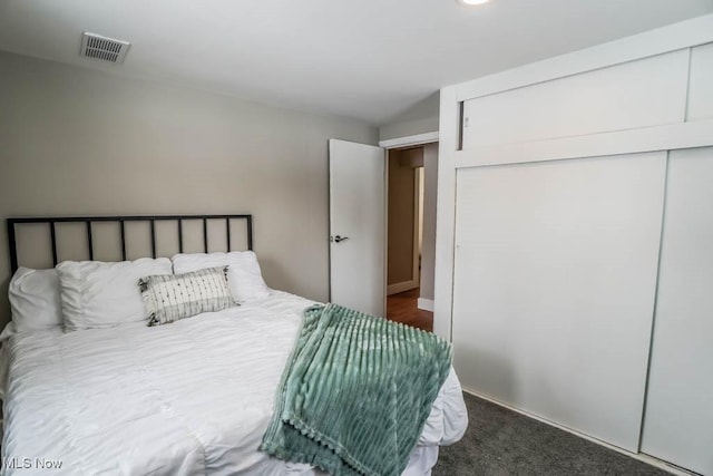 carpeted bedroom with visible vents and a closet
